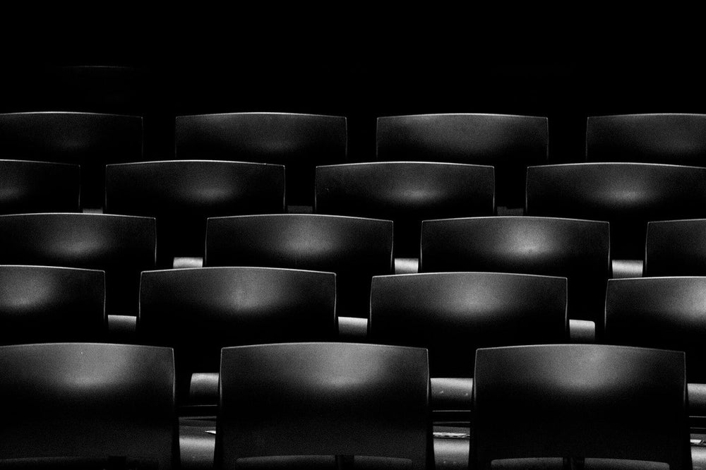 Rows of empty movie-theater seats in a dark auditorium.